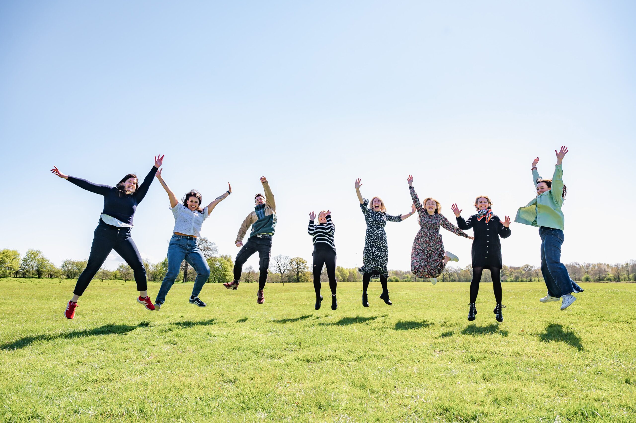 The Jack & Grace team jumping in the air, outside on a bright sunny day