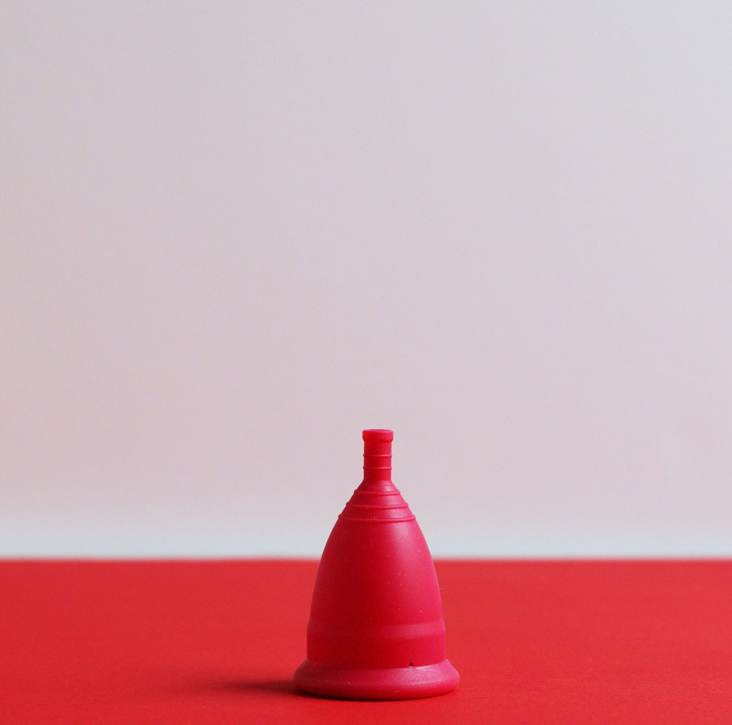Image of red mooncup on a red table against a light grey background