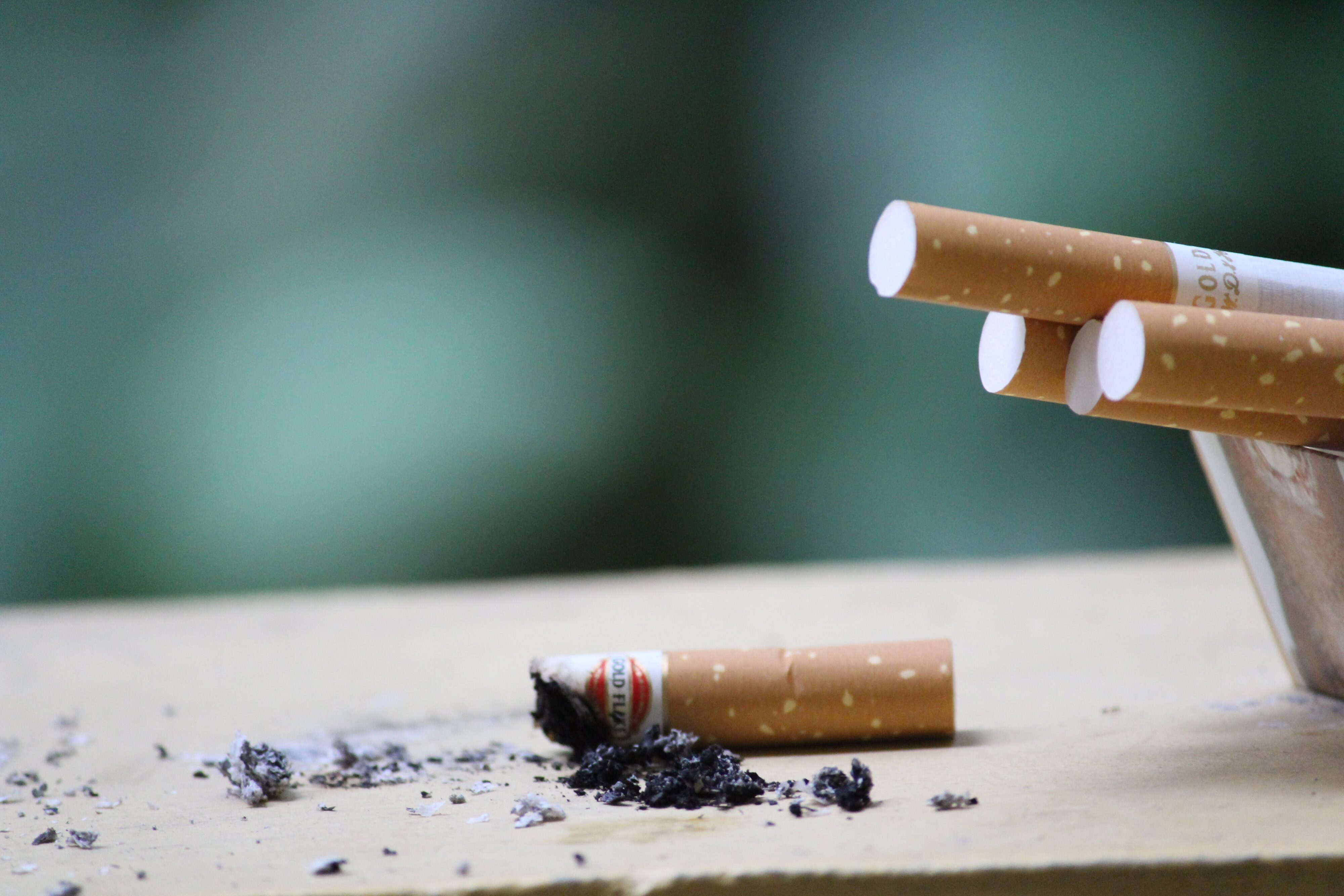 A smoked ciarette butt next to unsmoked cigarettes
