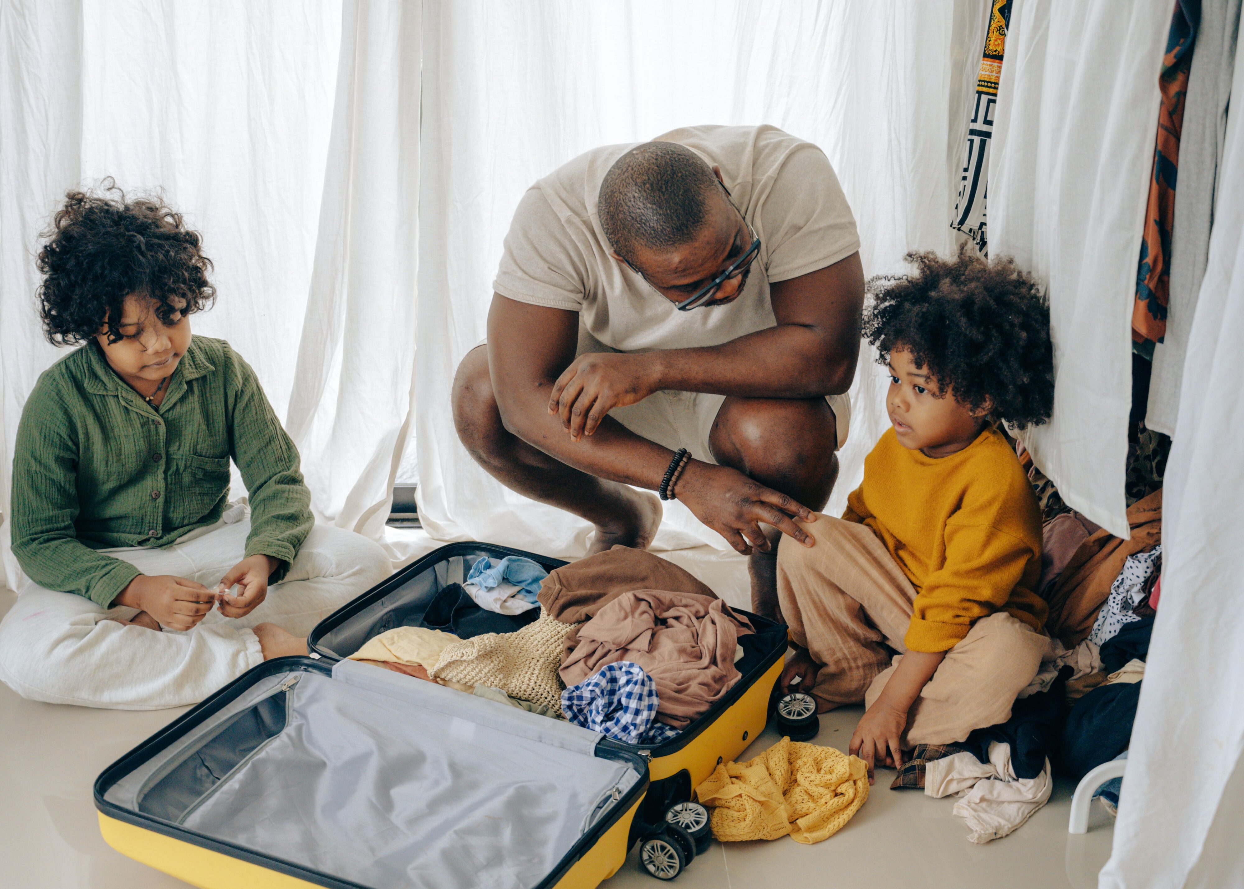 Man and two children pack a suitcase.