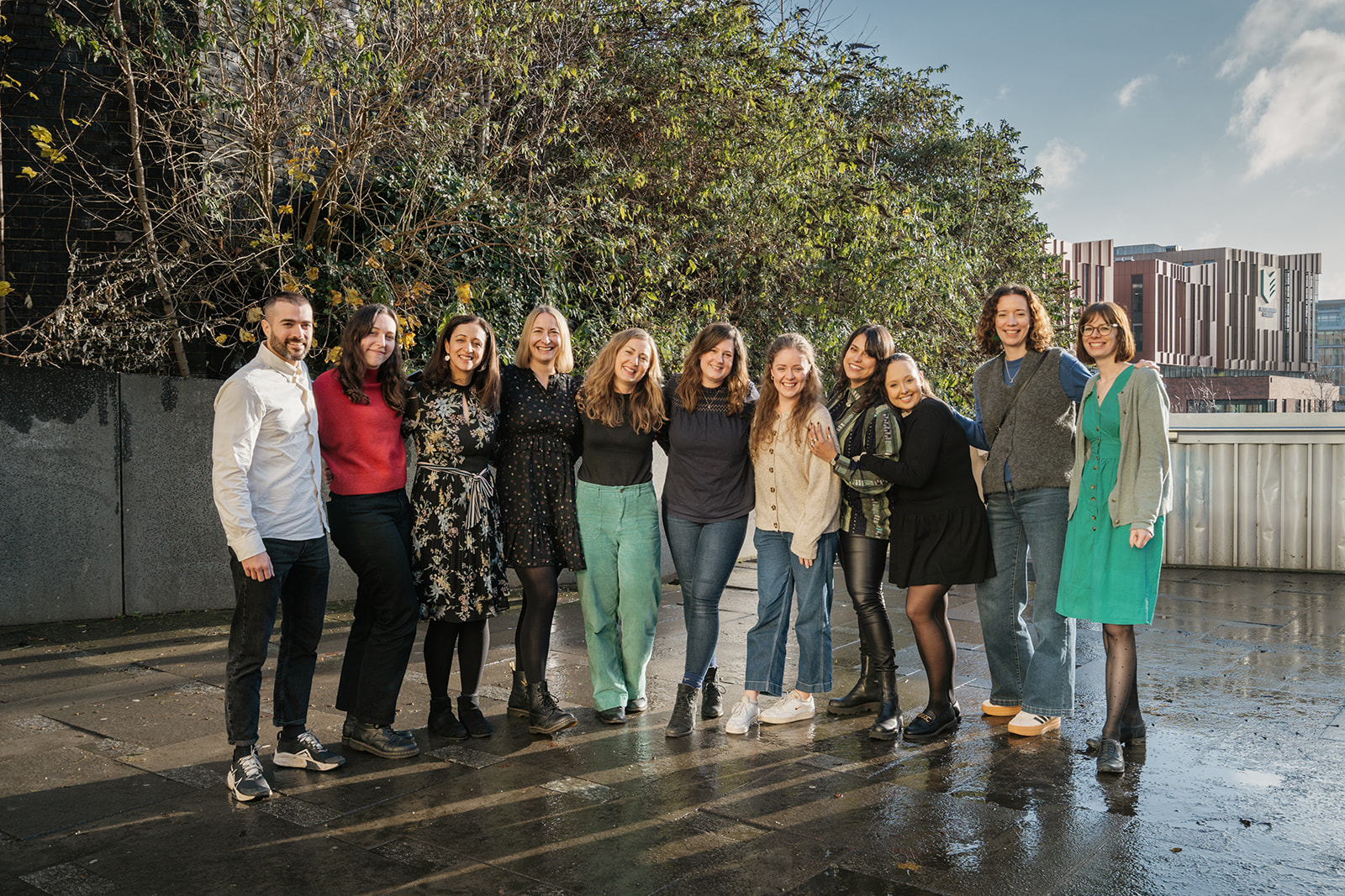 The Jack & Grace team standing outside in front of an autumnal tree. The team is smiling and linking arms.